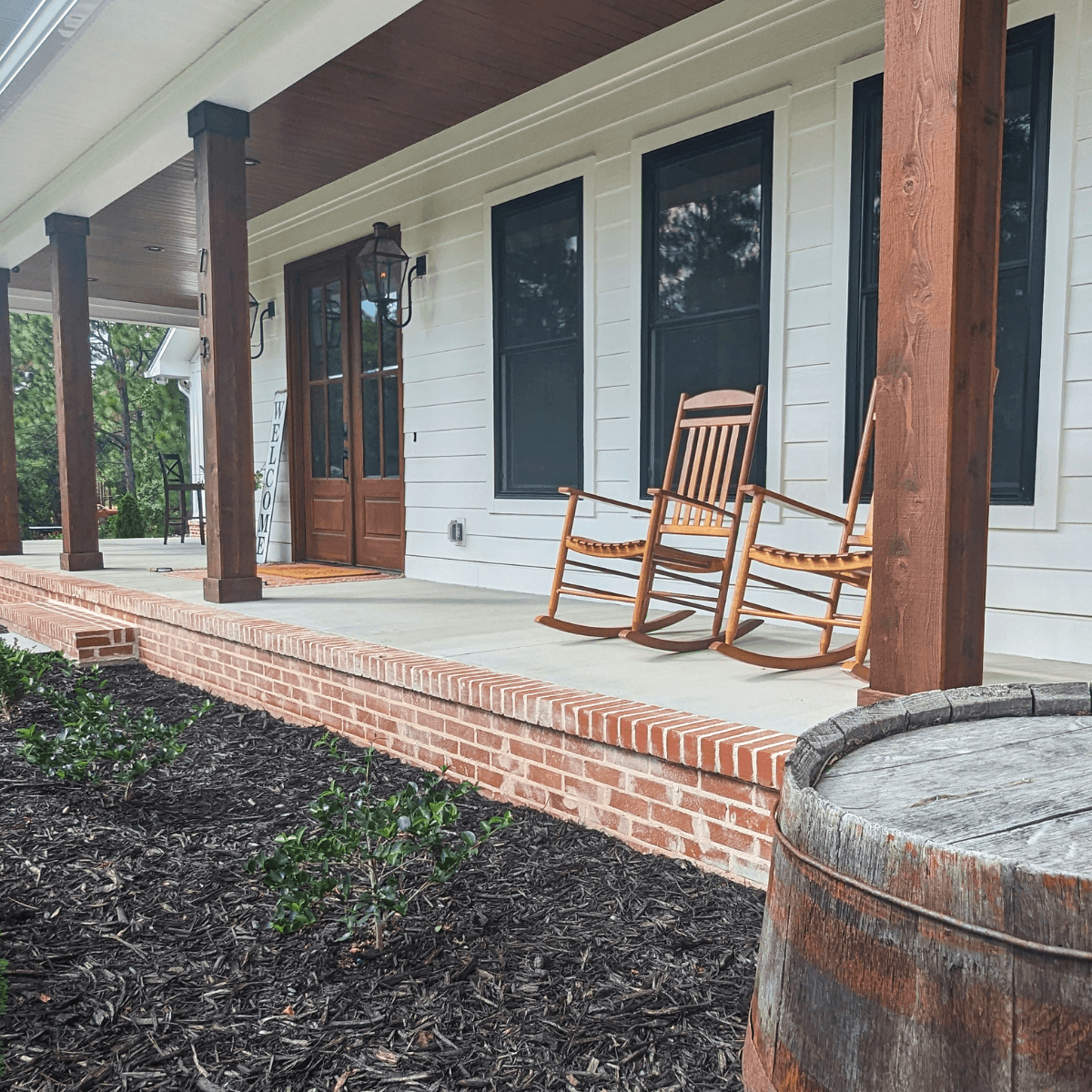Newly built house with a covered front porch featuring wooden columns and rocking chairs