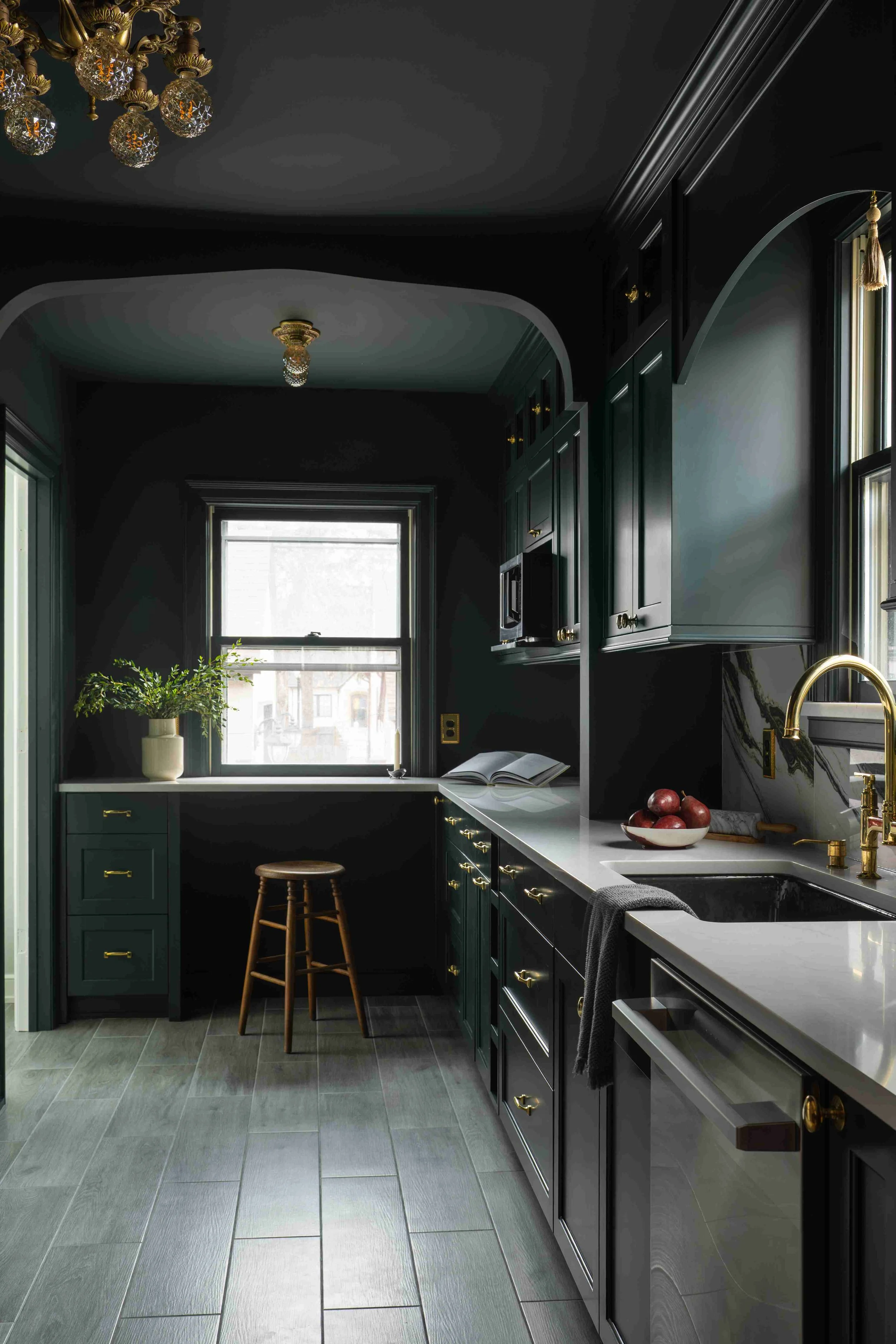 Dark green custom kitchen remodel with
brass chandelier and arched millwork,
Minneapolis