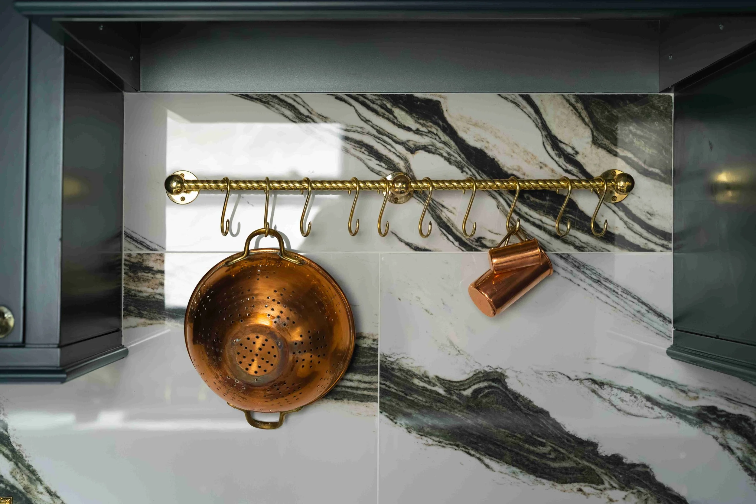 Brass pot rail and copper cookware storage,
dark green kitchen cabinets, Minneapolis