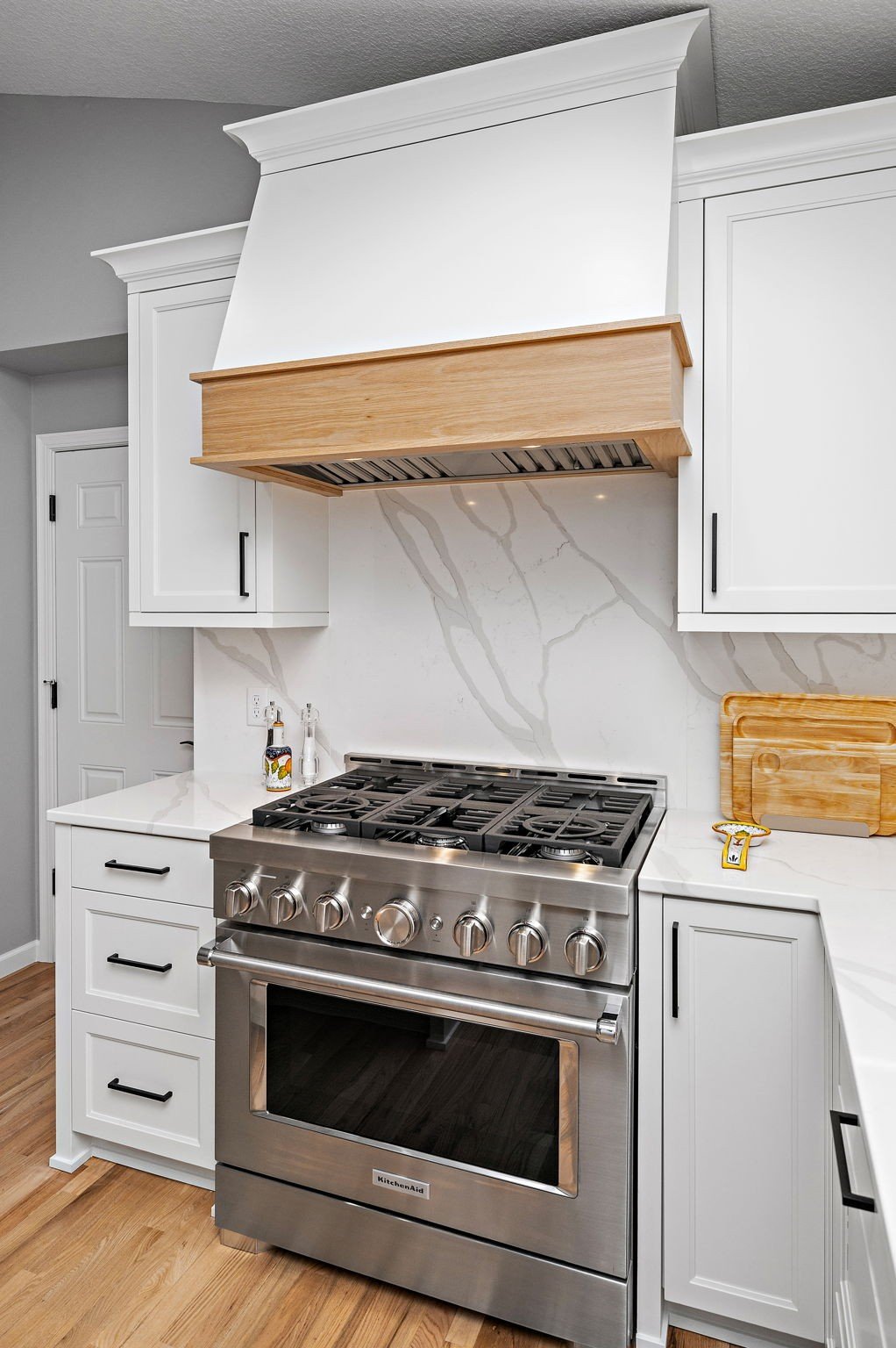 Custom wood-clad range hood over gas
range with quartz slab backsplash,
Minnetonka