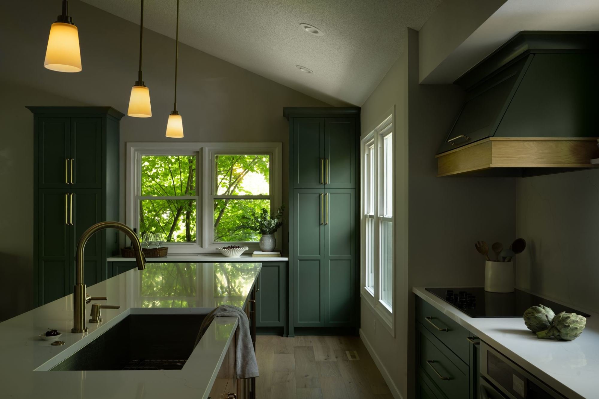 Window above green base cabinets with a white quartz countertop and tree views