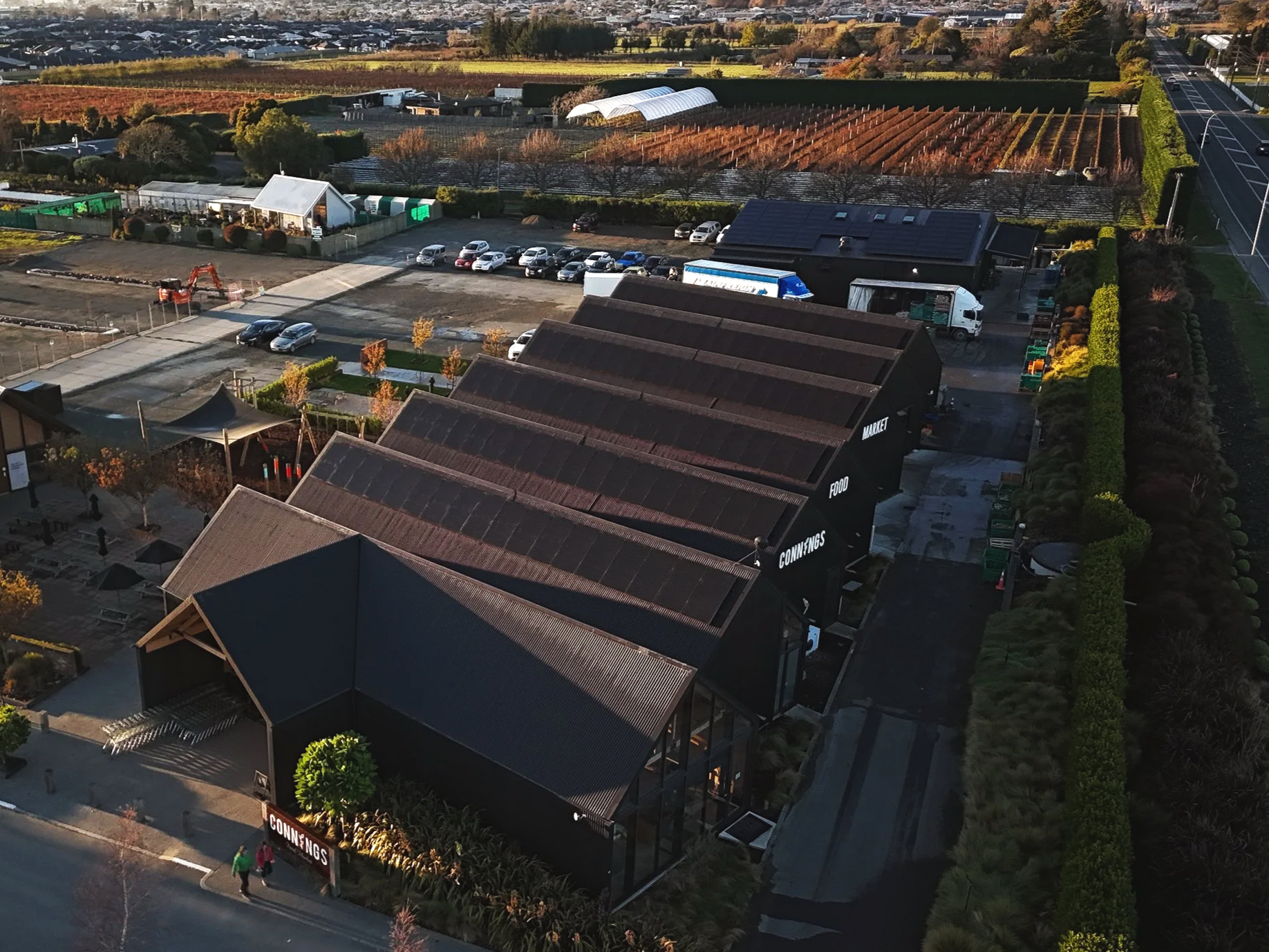 Aerial view of the Connings super market, and their lot with cars, a green landscape, a vineyard, and a road with pedestrians. Rowan Dron Electrical Installed the solar panels on this roof.