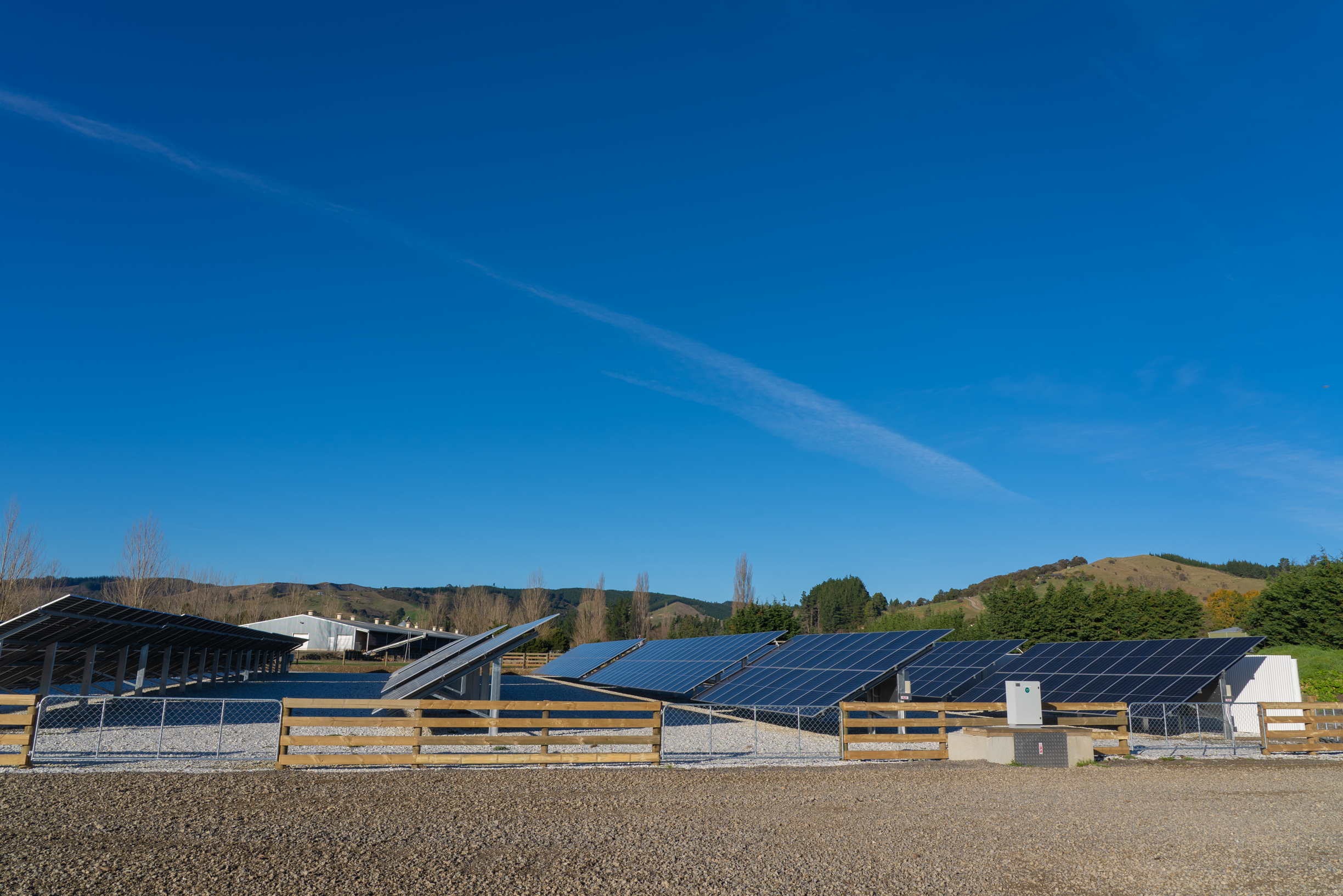 Solar panels installed in a field with mountains and a blue sky in the background.