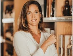Femme souriante dans une cuisine avec des meubles en bois et des objets décoratifs.