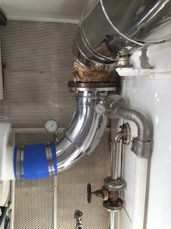 Custom stainless steel exhaust riser installation for marine engine applications.