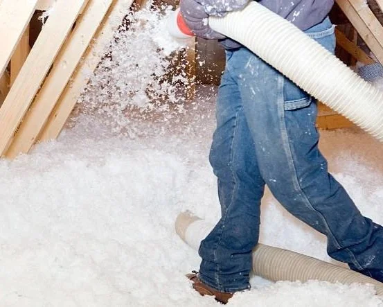 Man using a insulation hose to install insulation in an attic