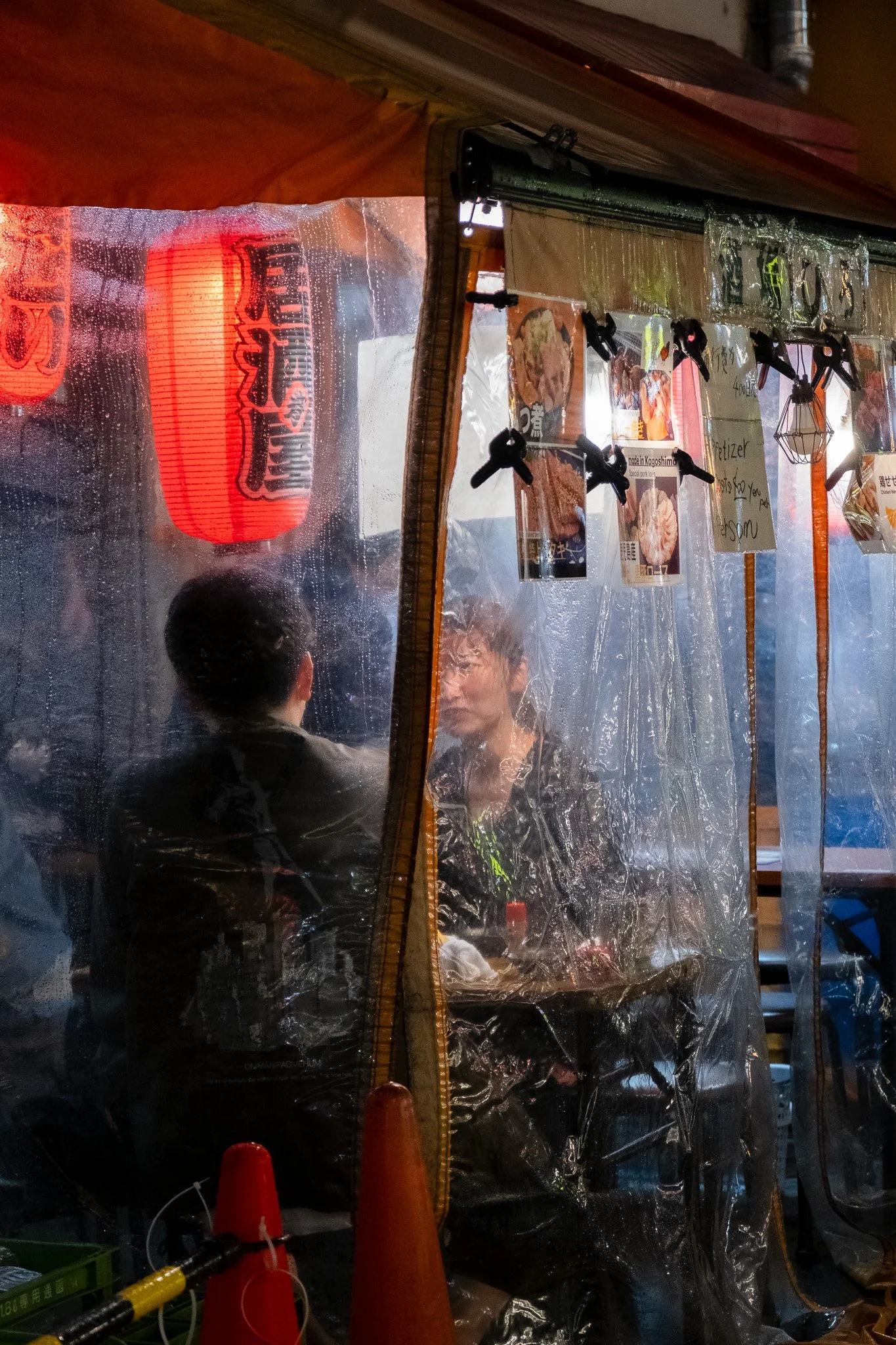 People dining inside a small Tokyo street restaurant on a rainy night.