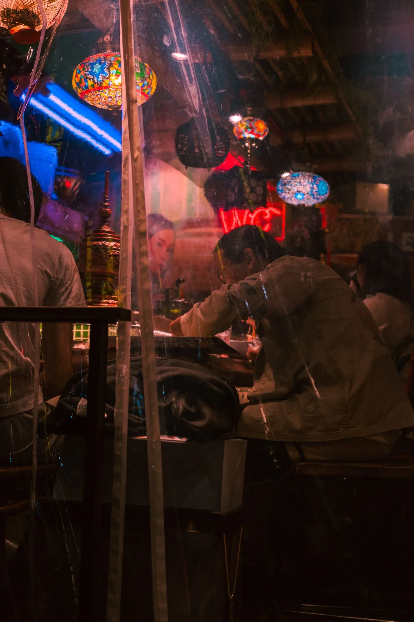 Inside a small Tokyo restaurant glowing with colorful night lights.