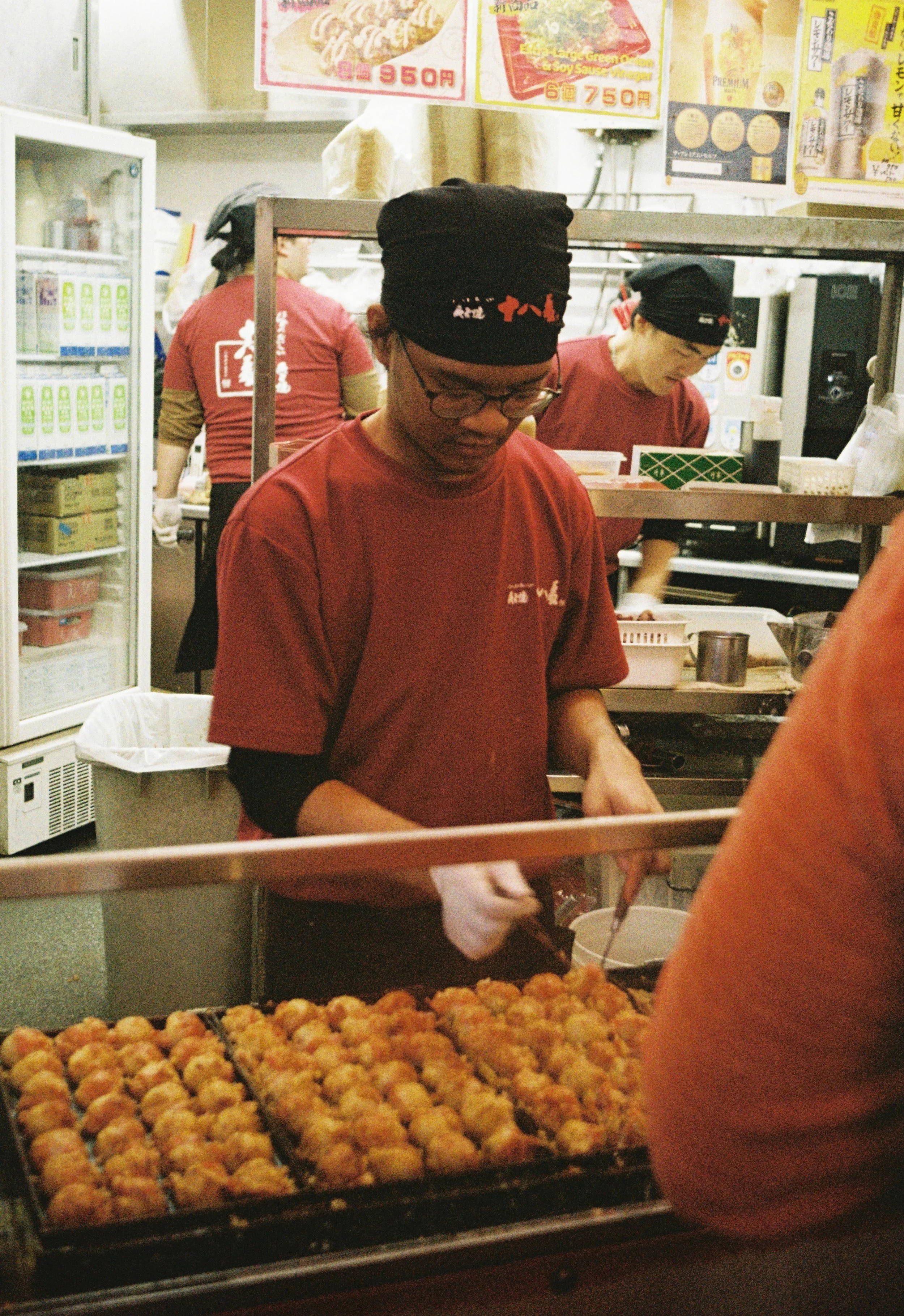 Street food vendor preparing takoyaki in Osaka captured on analog photography.”