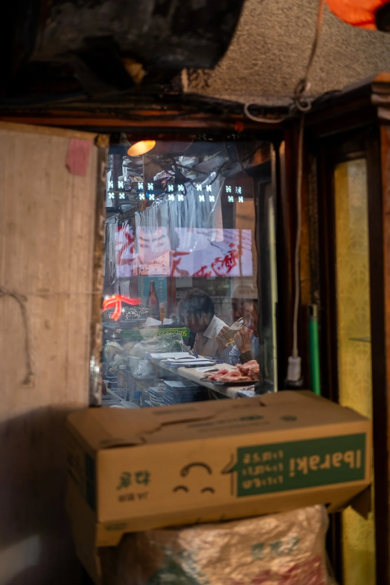 Small kitchen window inside a Tokyo alley restaurant at dusk.