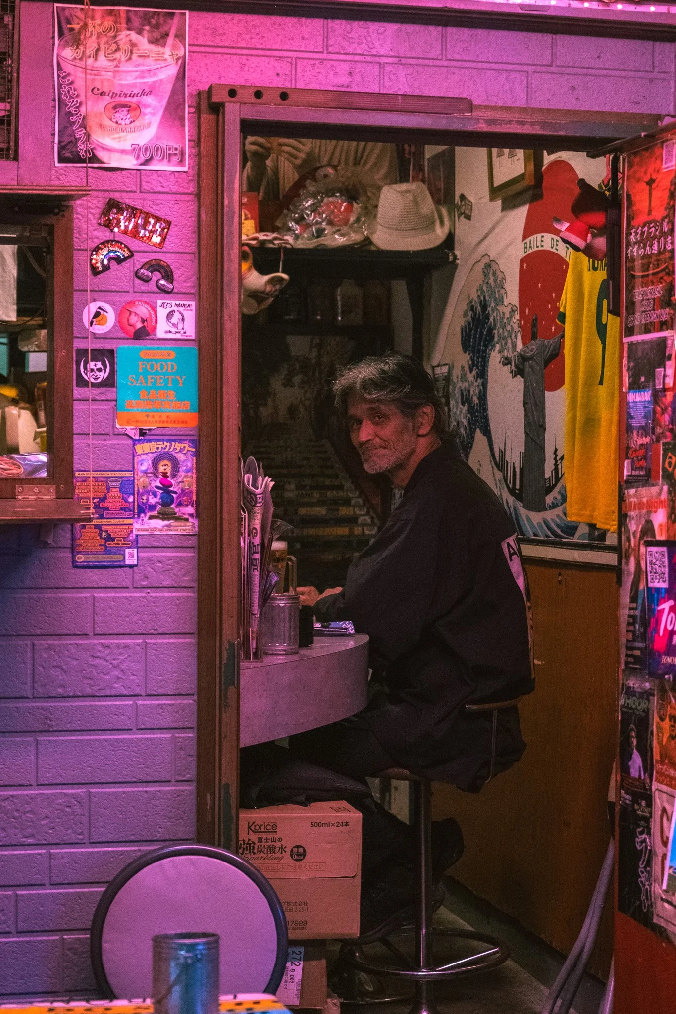 Portrait inside a neon-lit Tokyo shop during a rainy evening.
