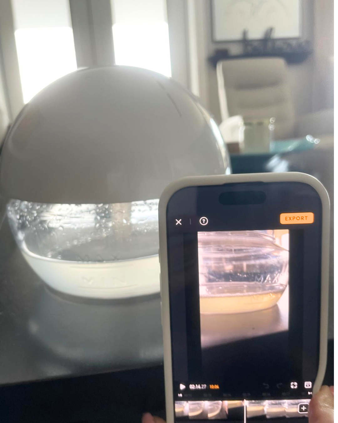 A smartphone holding a video recording of a humidifier on a table, with the humidifier visible in the background.