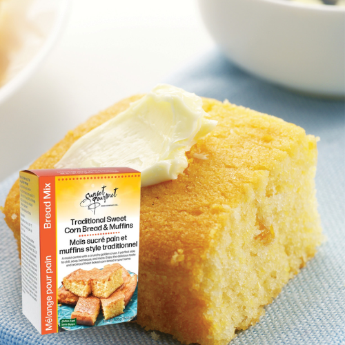A cornbread muffin with a dollop of butter on top, placed on a light blue napkin.