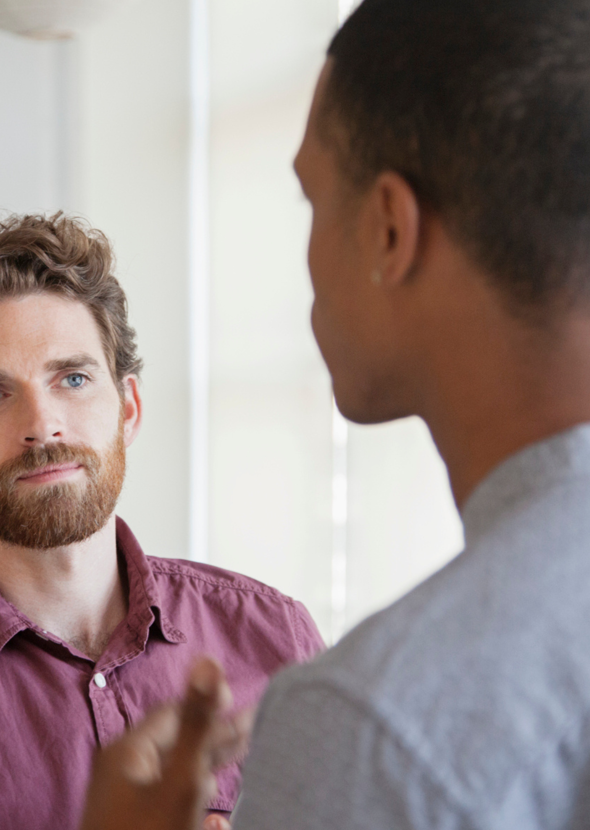Two men engaged in conversation, with one man facing the camera and the other with his back partially visible.
