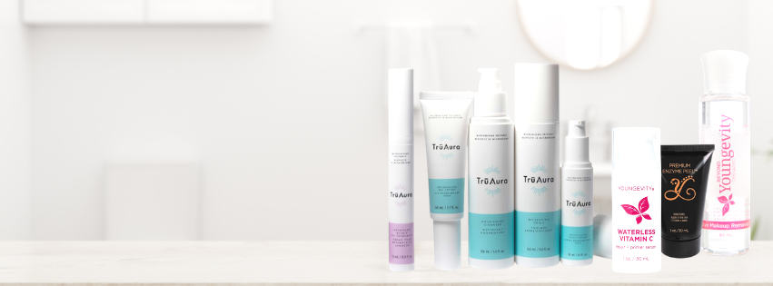 Collection of skincare products arranged on a white surface in front of a white wall.