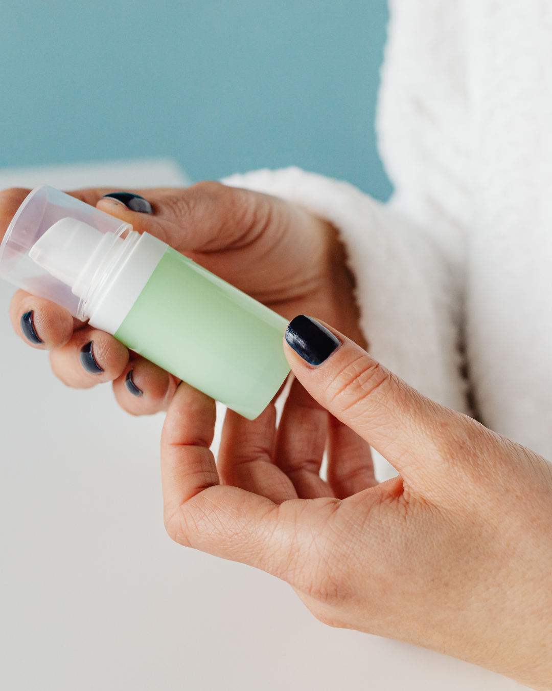 Person holding a small green pump bottle with a white pump dispenser.