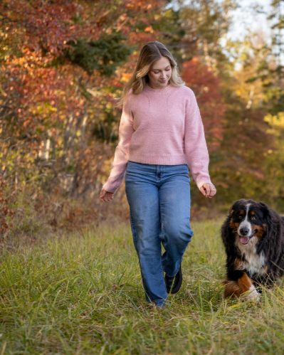 Young woman walking with a dog outdoors in fall foliage