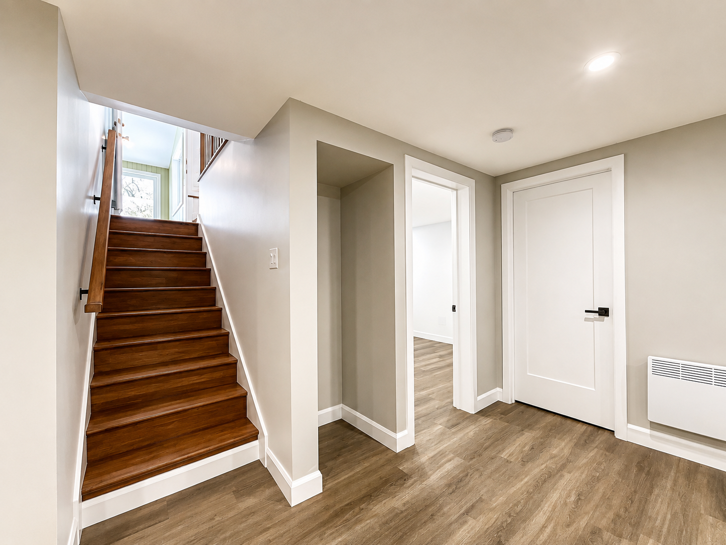 Rénovation de sous-sol réalisée par Garcia Construction Rénovation à Québec, avec escalier fini, plancher effet bois, éclairage encastré et finitions claires aux tons neutres.