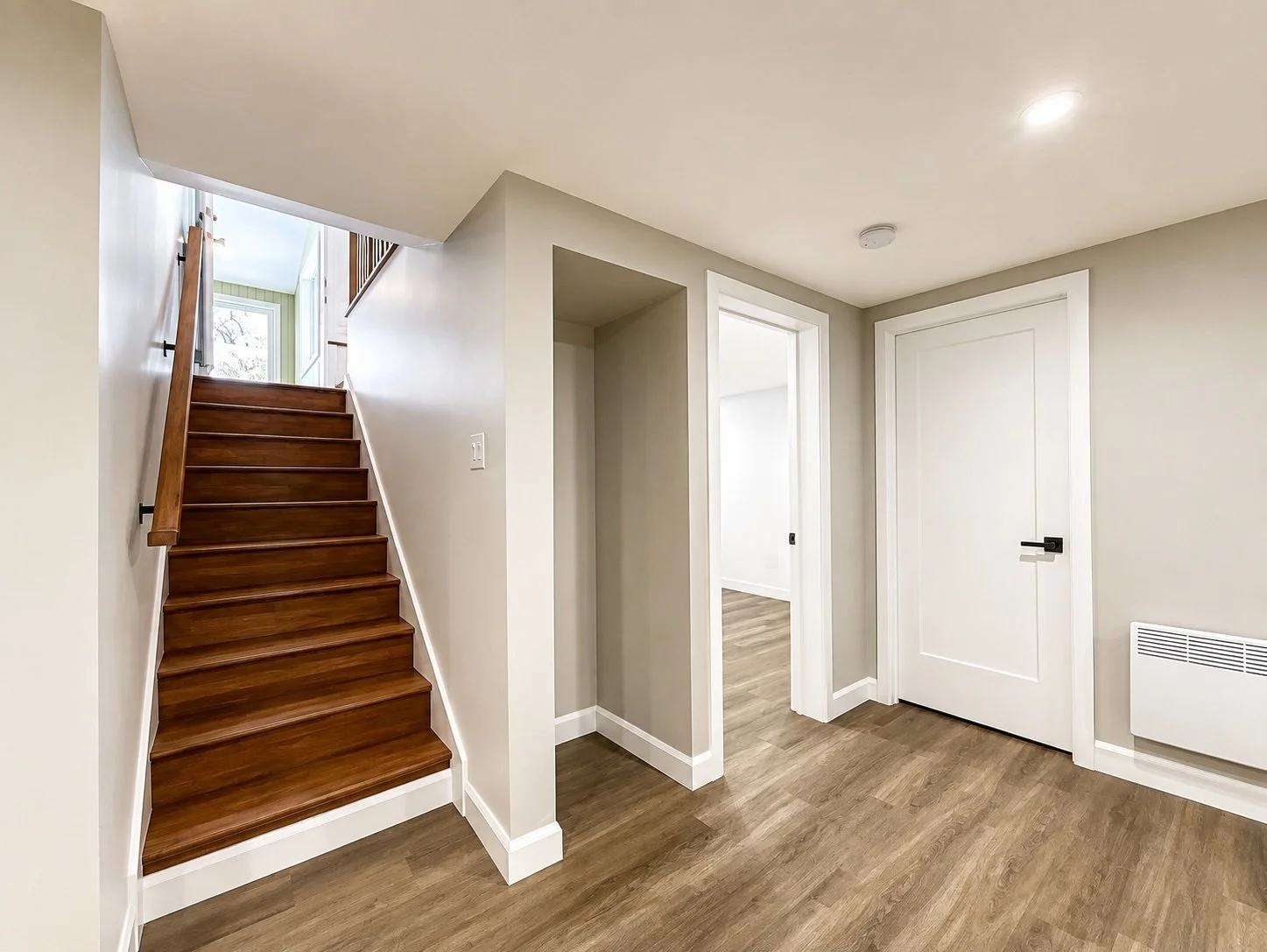 Basement renovated by Garcia Construction Rénovation in Quebec City, with a wood staircase, vinyl flooring and modern finishes.