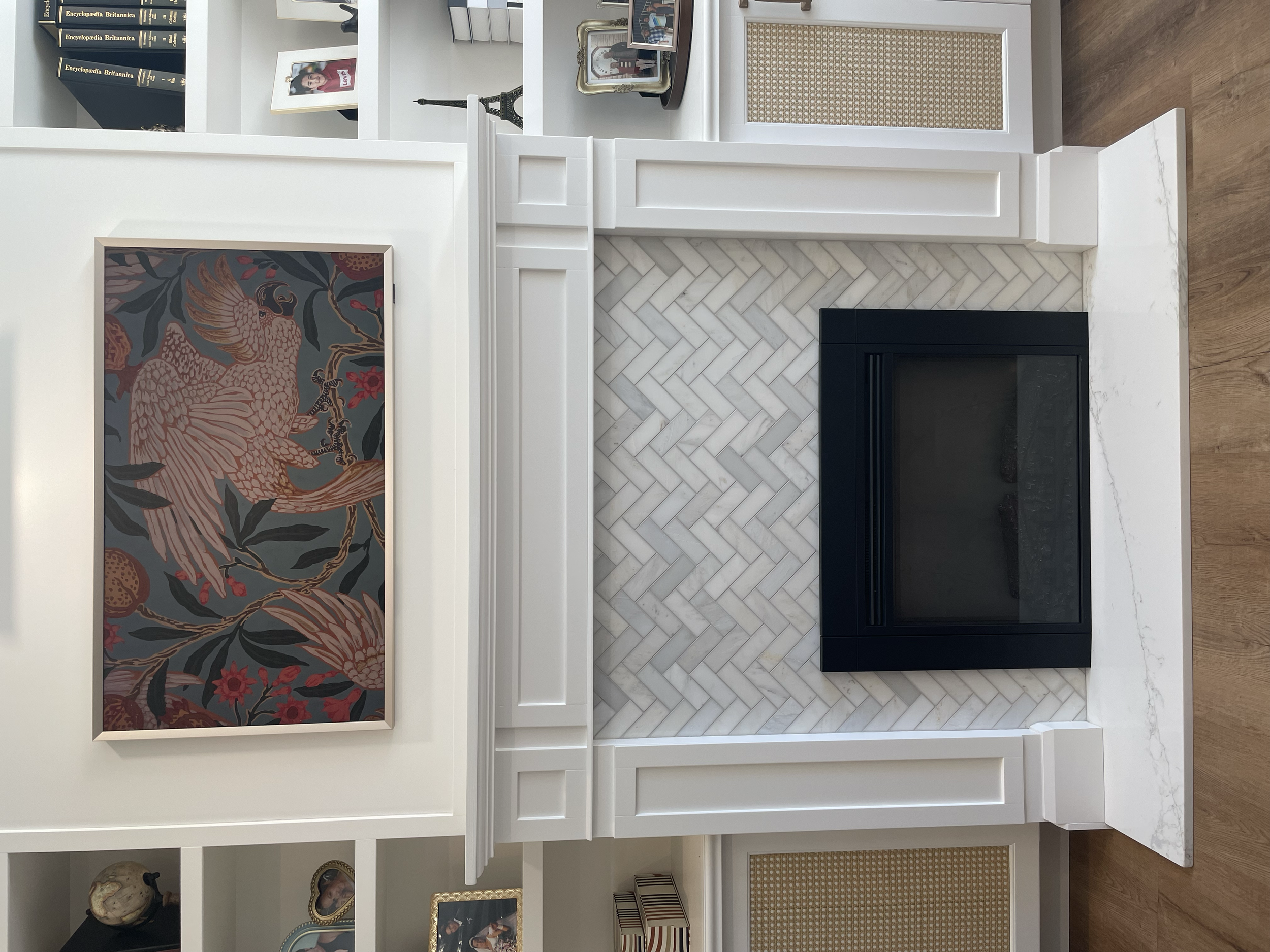 Custom fireplace renovation by Garcia Construction Rénovation in Quebec City featuring detailed white millwork, herringbone tile and built-in shelving.