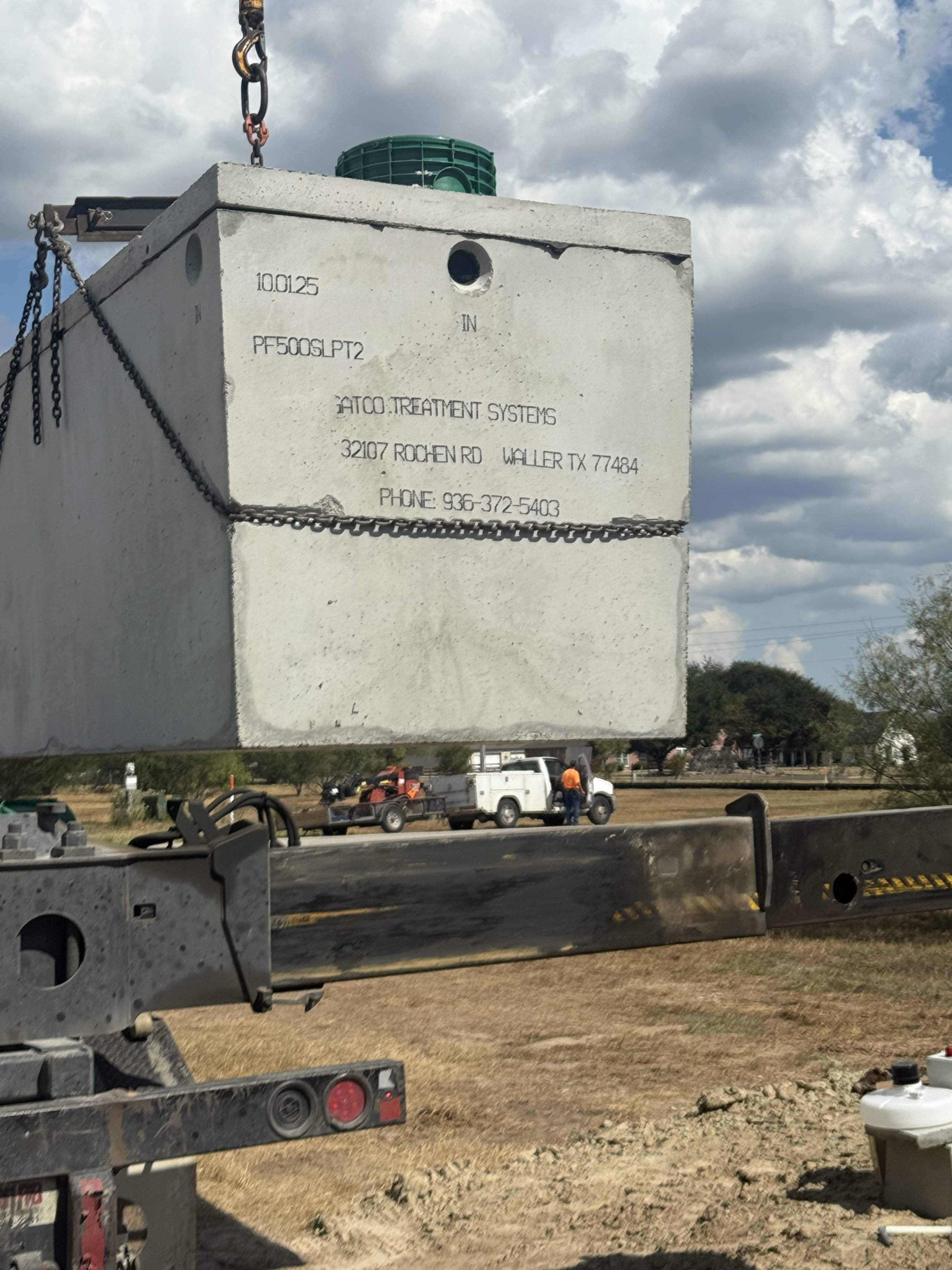 Construction site with large white concrete septic tank being installed on a property.
