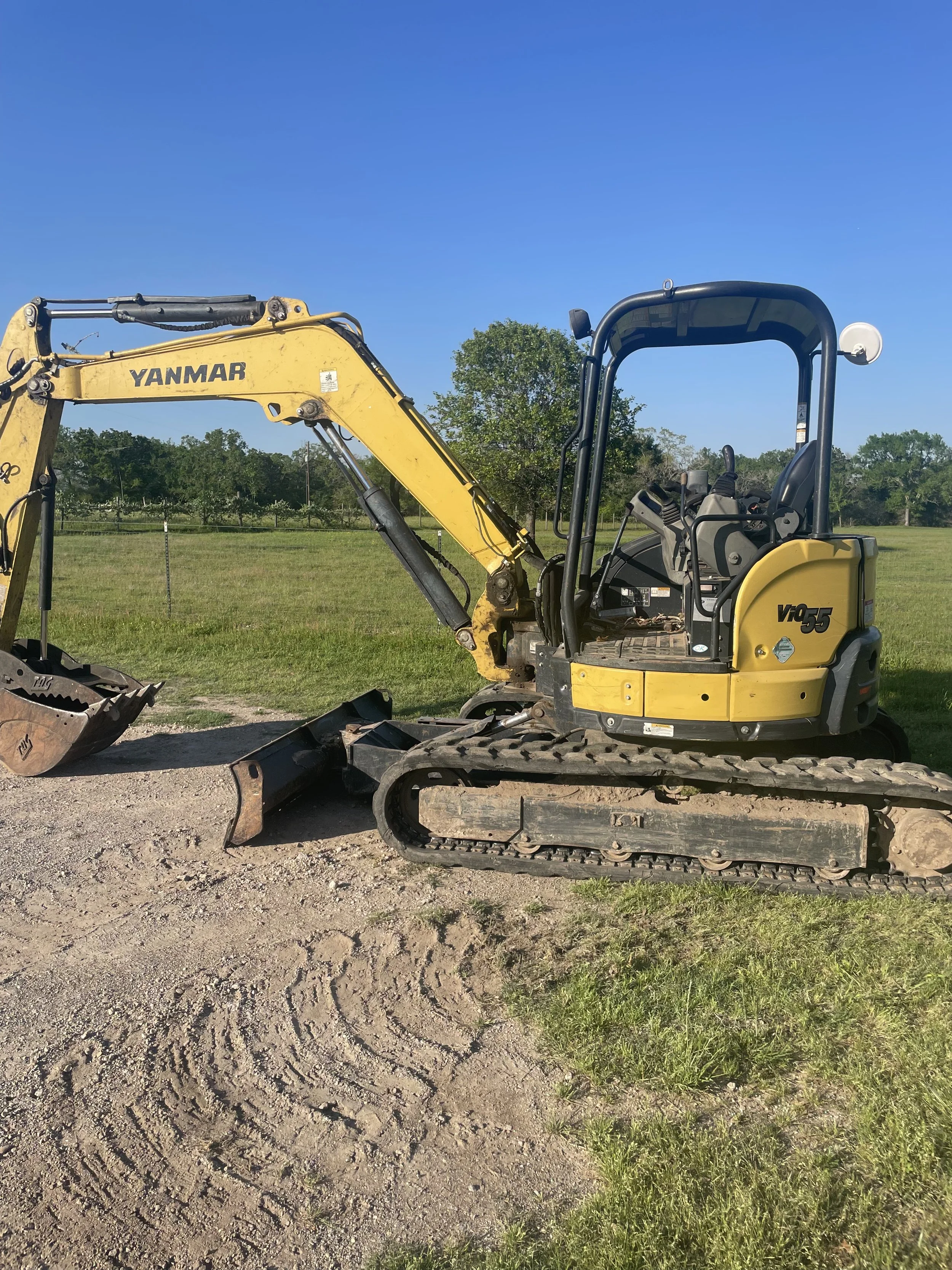 A yellow Yanmar mini excavator ready to dig a trench for a new septic system.