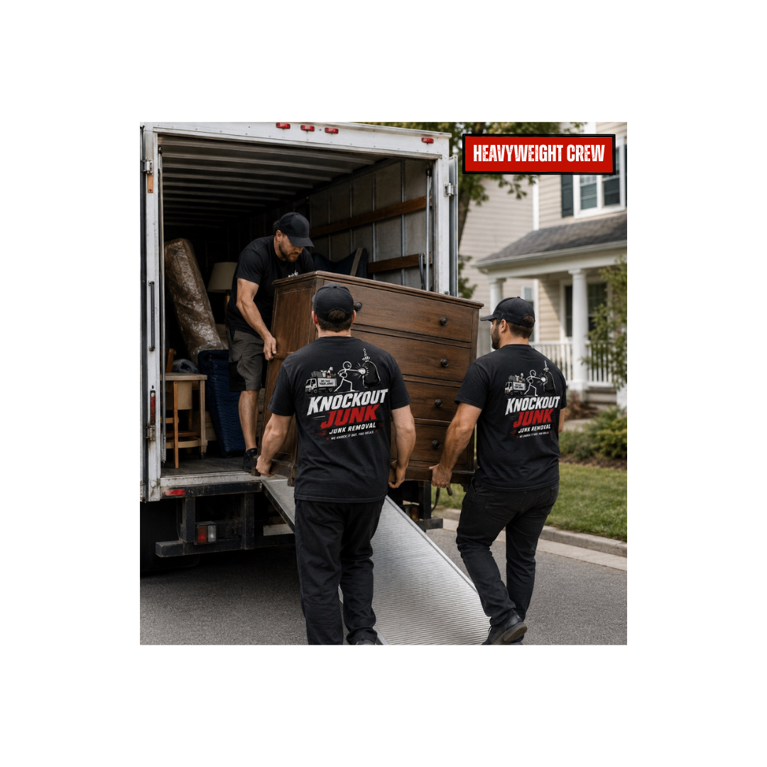 Three men loading furniture into a moving truck, wearing black shirts with 'Knockout Junk' logo, in a residential neighborhood.