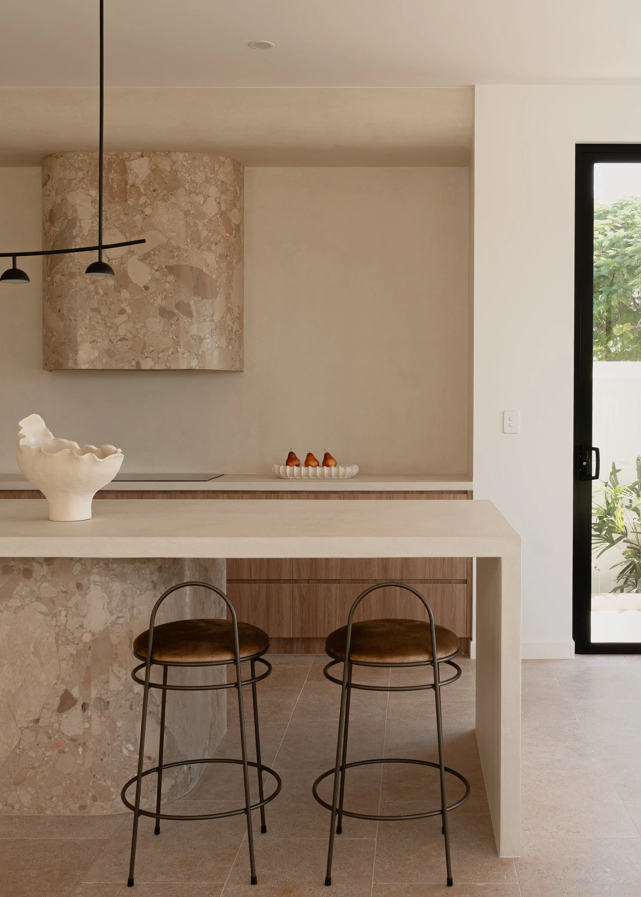 Modern kitchen with warm brown tones, featuring a marble island from Finestone granite with beautiful interior styling. detailed curved stone rangehood
