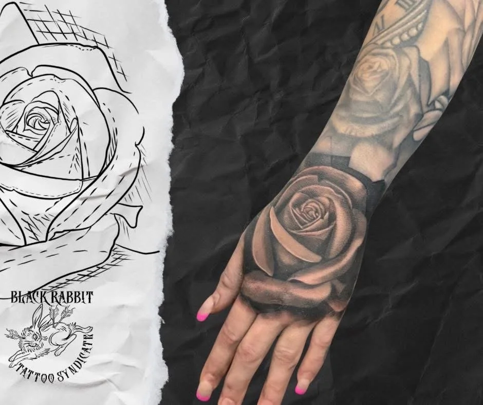 A realistic black and gray rose tattoo on a person's forearm.