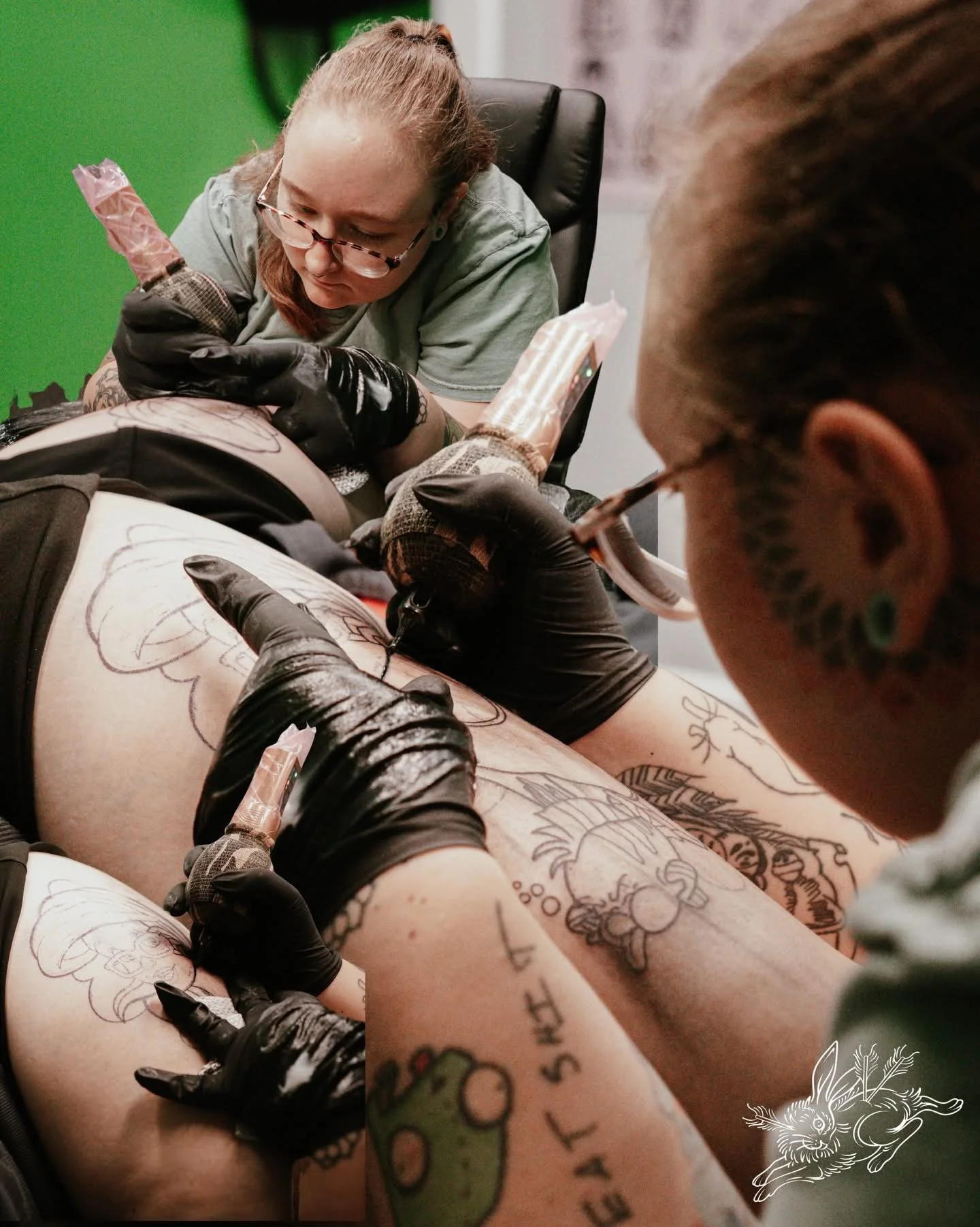 A tattoo artist creating tattoo designs on a person's leg in a studio.