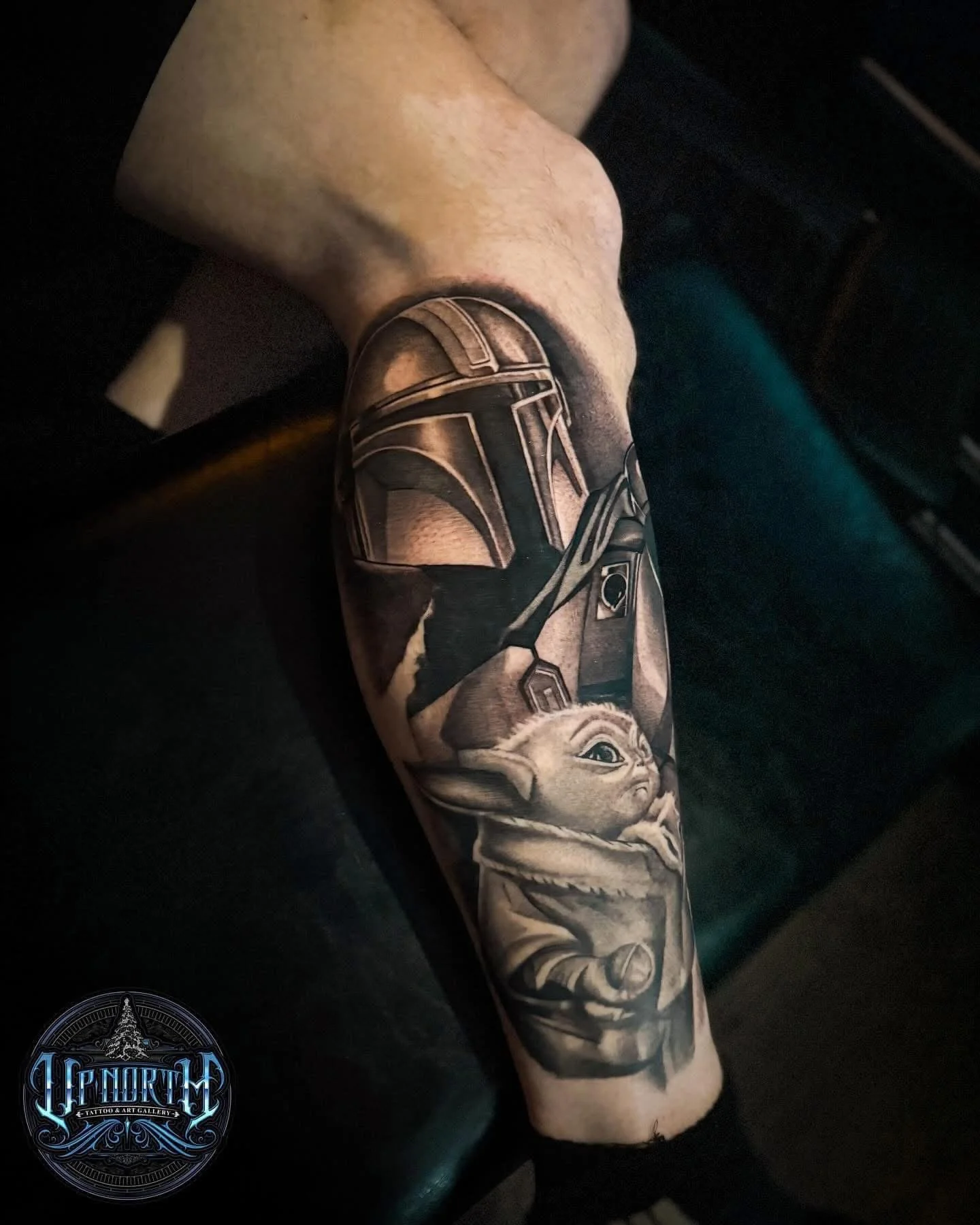 Tattoo of Baby Yoda from Star Wars on person's forearm.