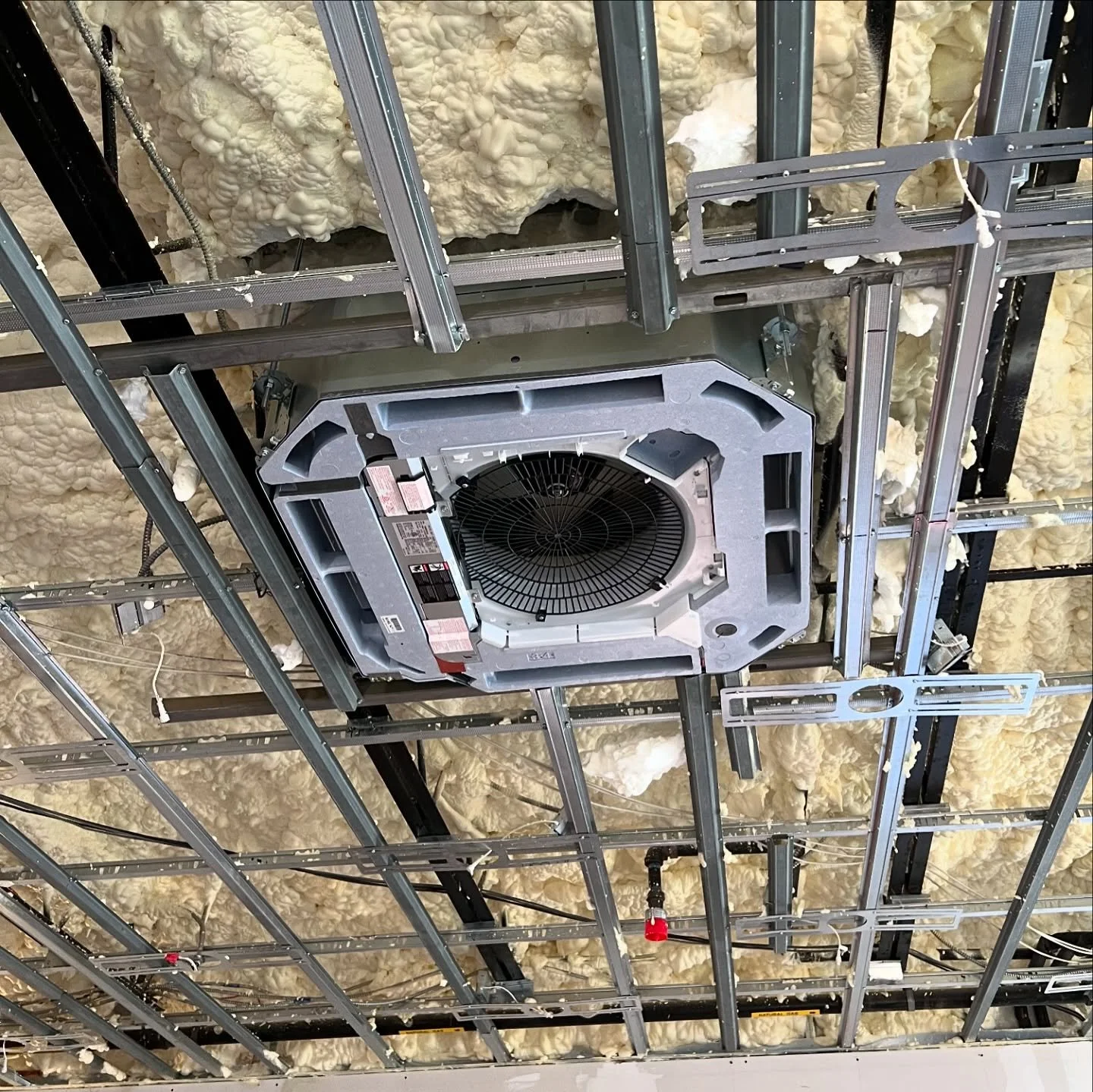 Ceiling framework with insulation foam, electrical wiring, and a central HVAC air handler unit.