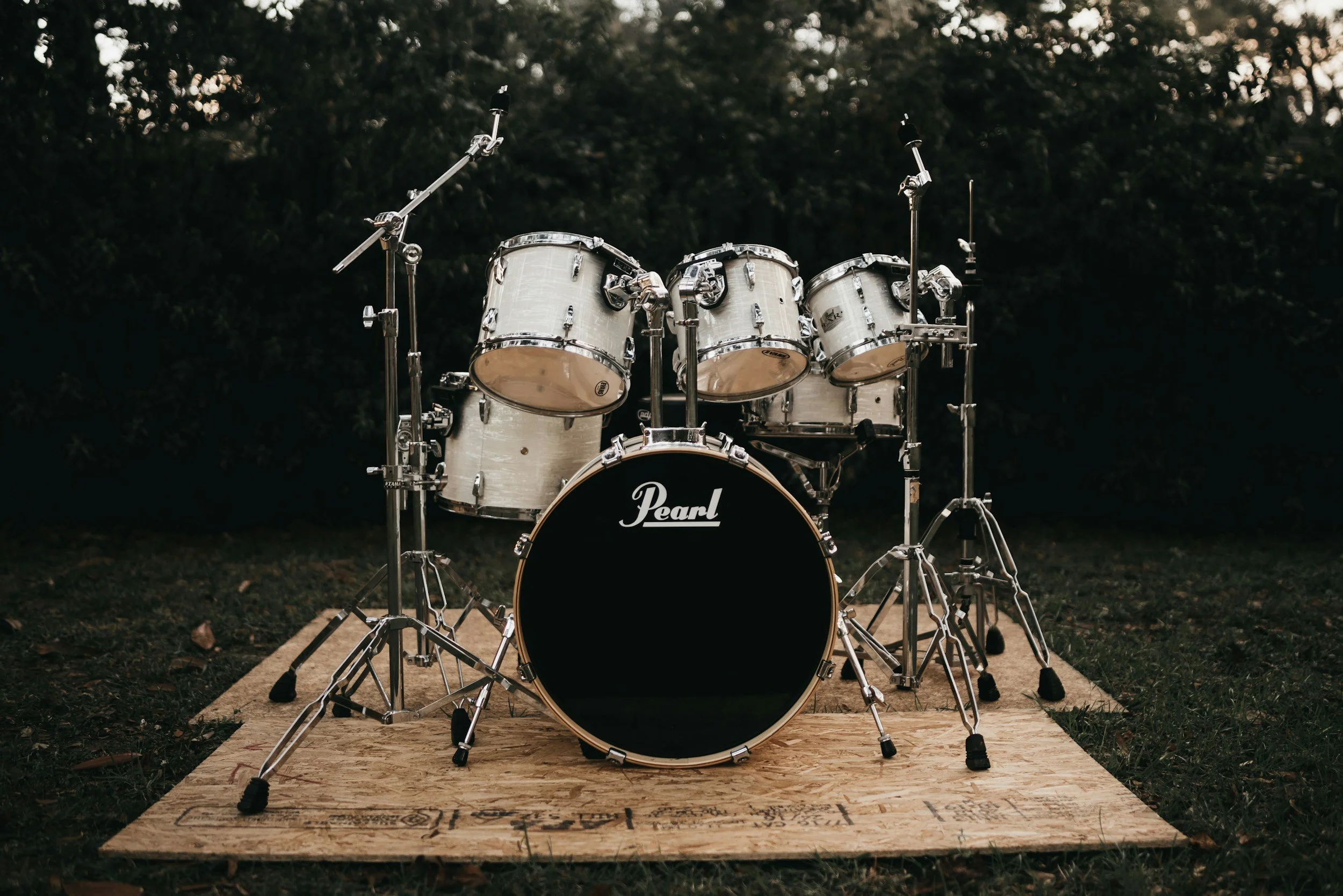 A set of drums on a wooden platform outdoors, with dark trees in the background.