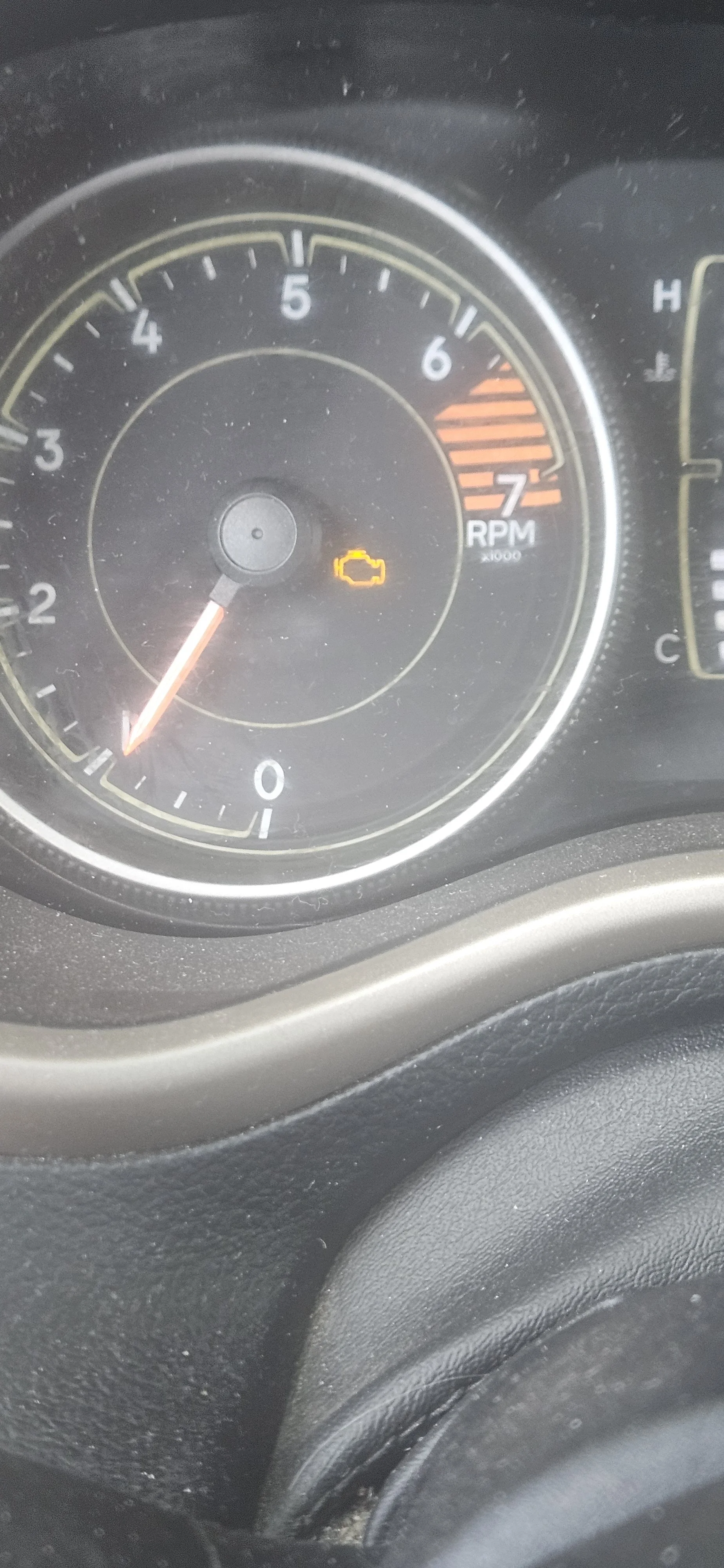 Car dashboard with a yellow check engine light illuminated and the tachometer showing around 850 RPM.