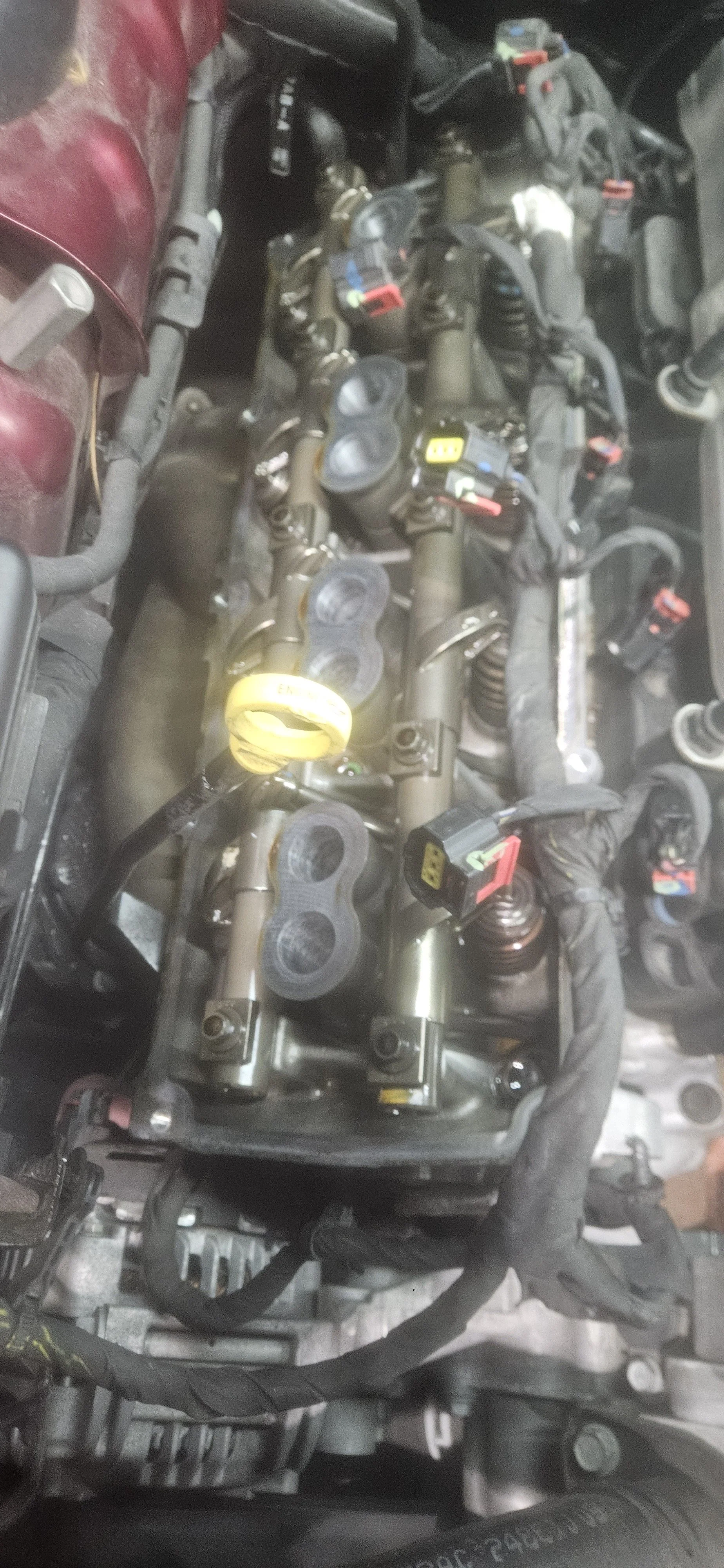 Close-up of a car engine with various parts, wires, and connectors, partially covered in dirt.