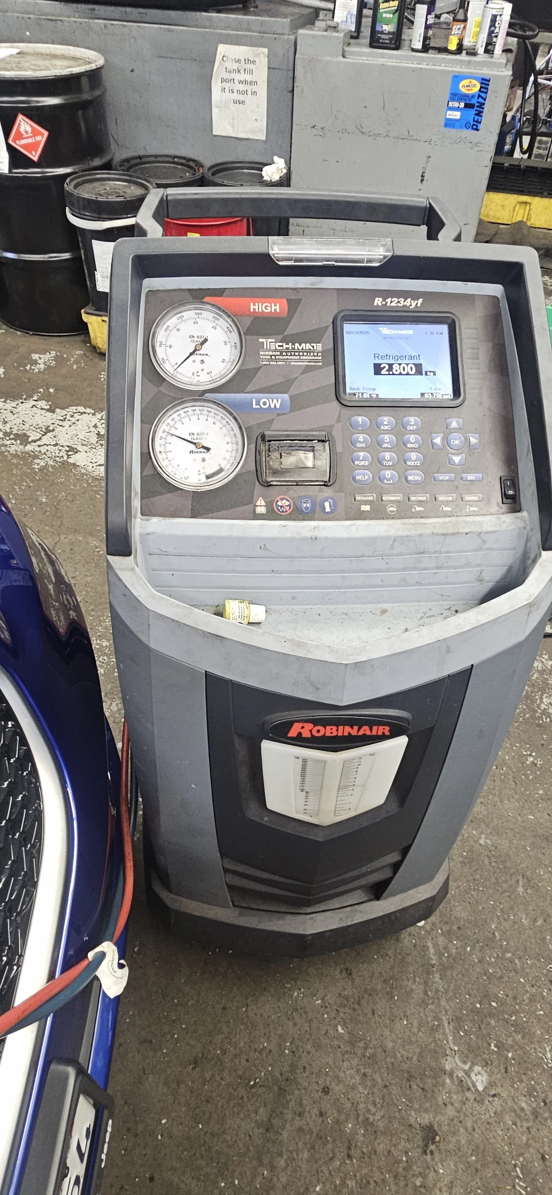 Automated vehicle air conditioning and refrigeration machine, with digital and analog gauges, and control panel, in a workshop setting.