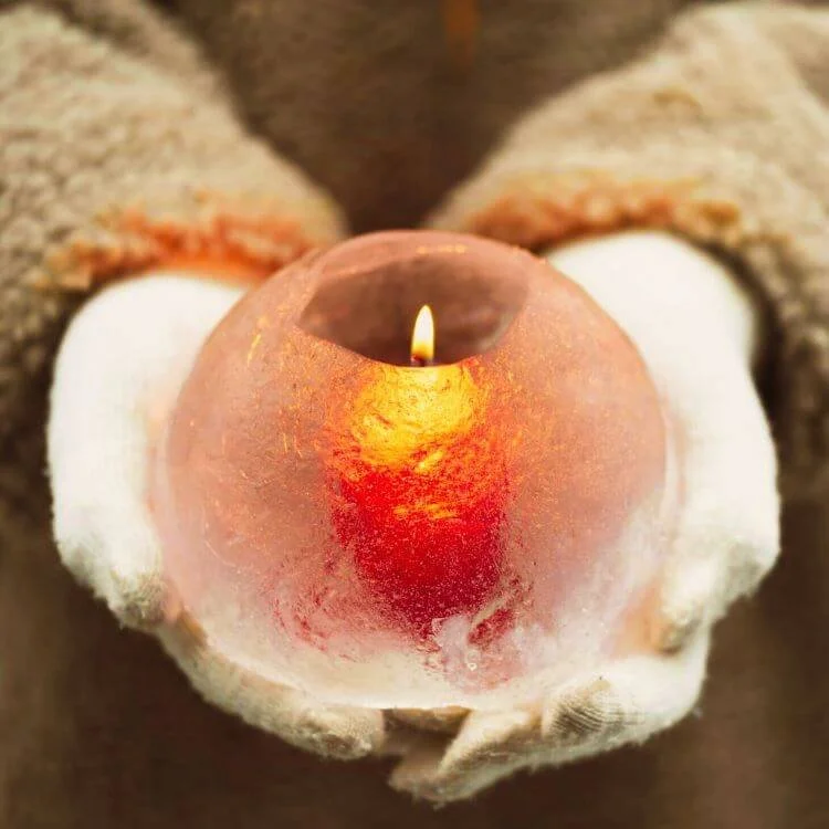 Person holding a small, lit candle inside a peach.