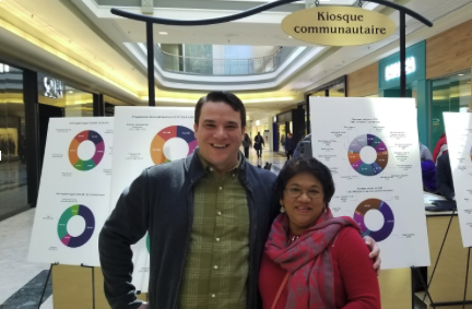 Matt Luloff standing in front of informational posters about community engagement in a shopping mall.