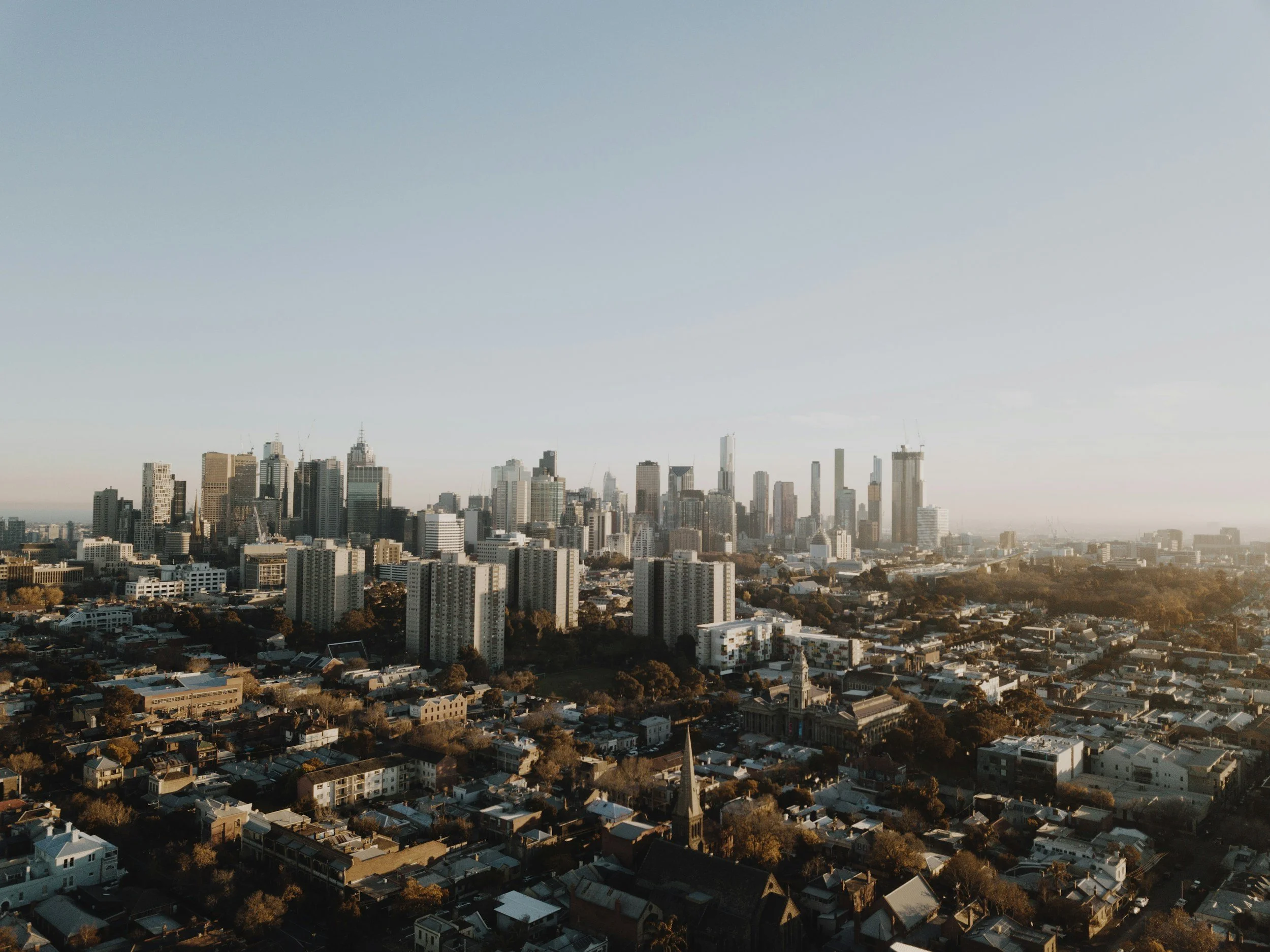 A city skyline with numerous tall buildings and skyscrapers under a clear blue sky.