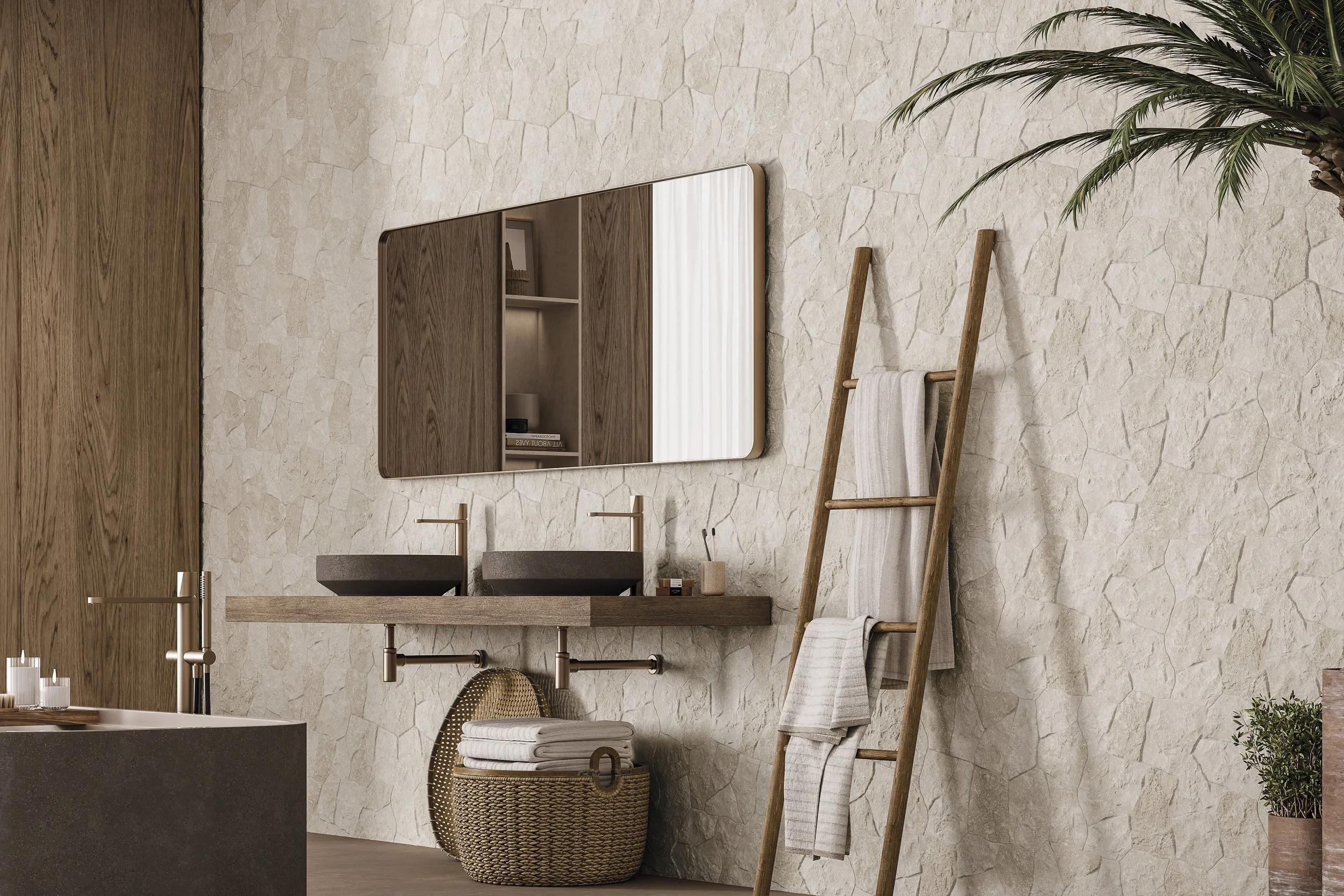 Un mur intérieur avec un miroir rectangulaire, une étagère en bois avec plusieurs objets, un lavabo en pierre, une panière en osier avec des serviettes blanches, une échelle en bois avec une serviette, un tapis beige et un plante verte en pot.