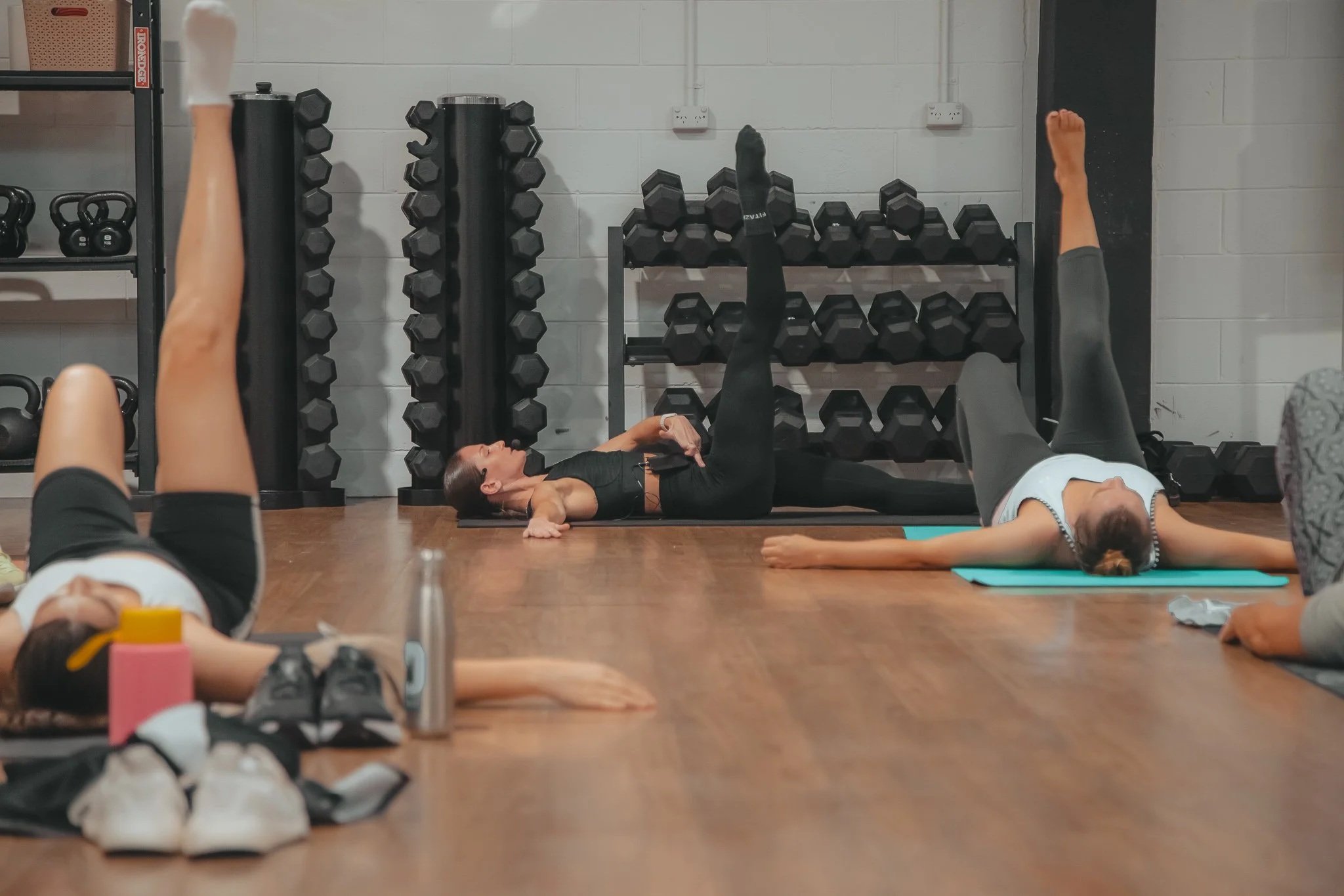 Professional trainer - Katie Baring-Gould. Image in a gym, performing mat Pilates class.