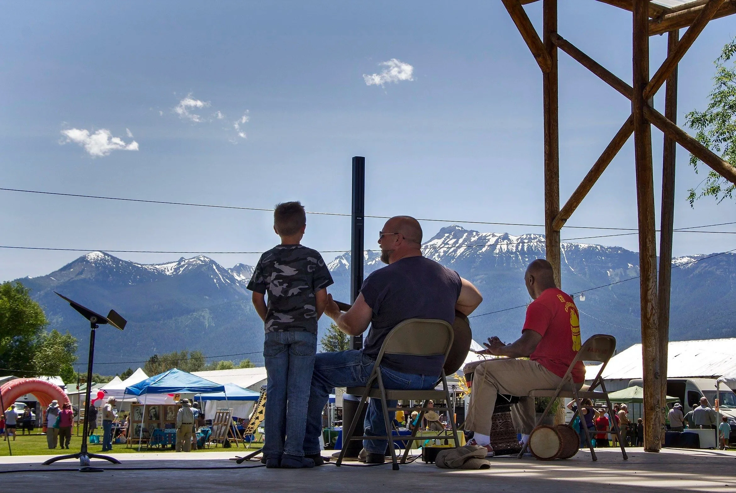 People gathered on a stage at an outdoor event with mountainous scenery in the background.