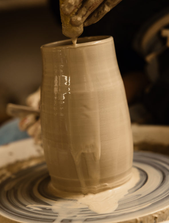 Un tourneur modelant une tasse en céramique sur un tour de potier.