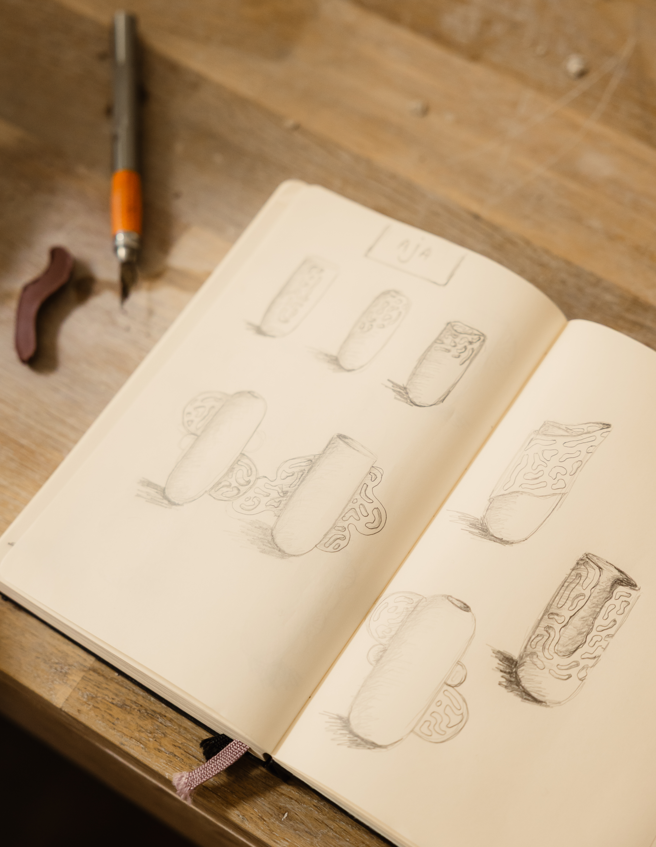 Dessins de cylindres avec motifs et textures différentes dans un carnet de croquis posé sur une table en bois.