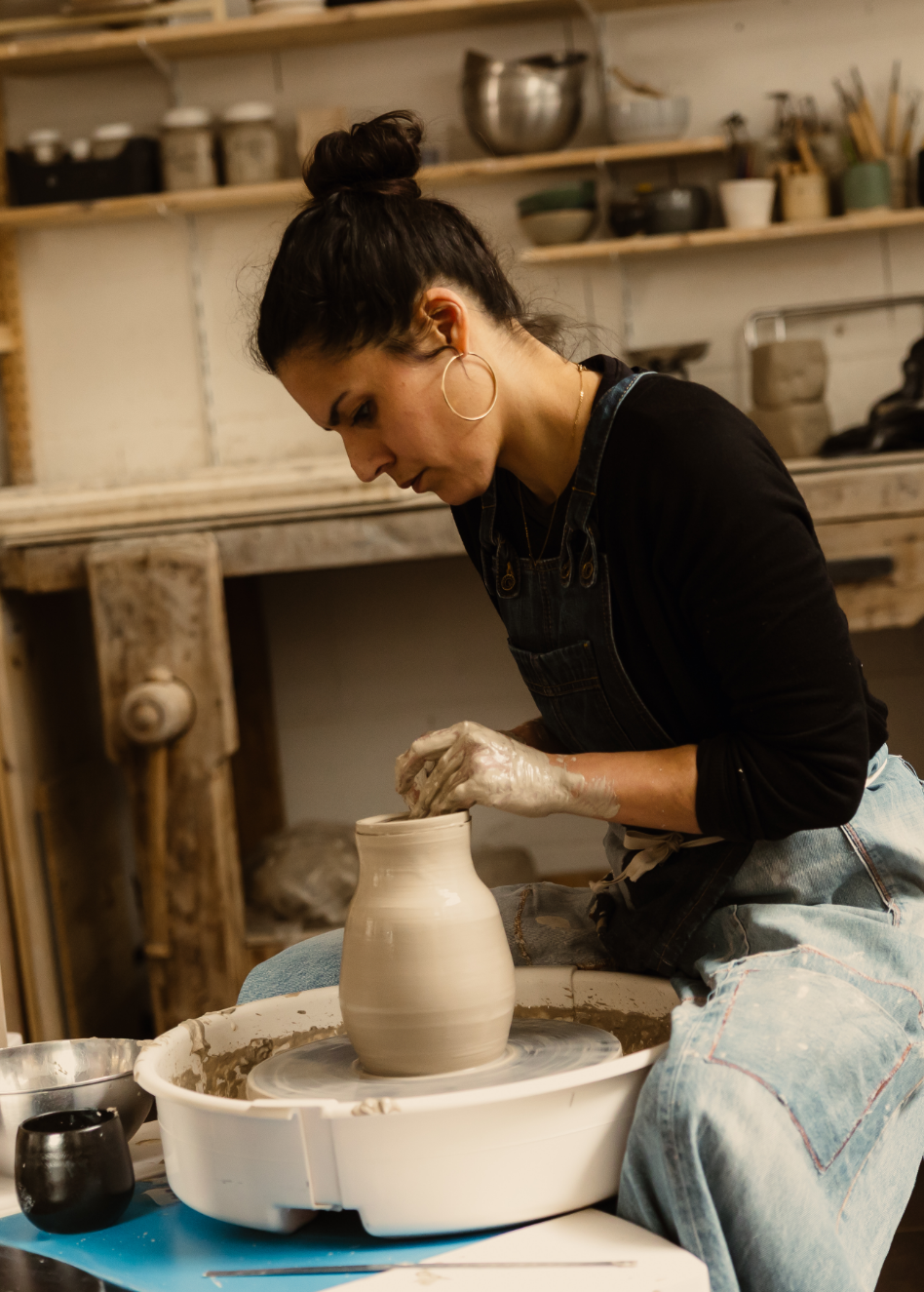 Femme créant une poterie sur un tour de potier dans un atelier