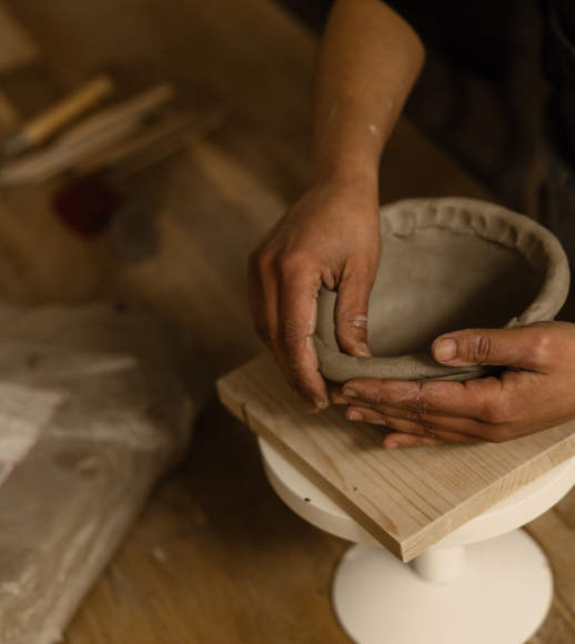 Personne façonnant une poterie en argile sur un tour de potier, dans un atelier de céramique.