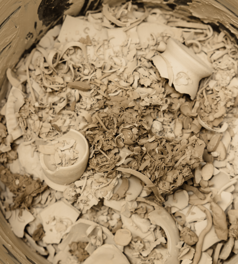 Débris de céramique cassée dans un contenant, comprenant des morceaux de vaisselle brisée comme des tasses, des assiettes et autres objets en porcelaine.