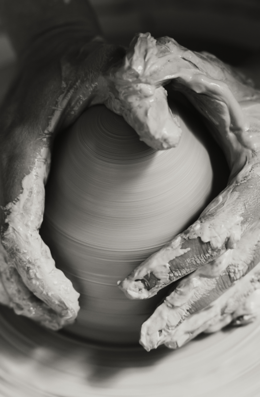 Main qui façonne de l'argile sur un tour de poterie.