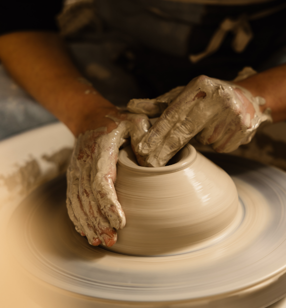 Mains d'artiste modelant une pièce de poterie sur un tour de potier.
