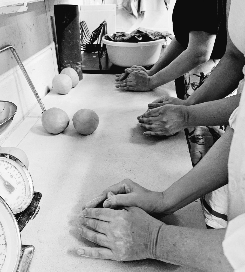 Groupe de personnes faisant de la pâte à modeler ou de la pâte à pain sur une table de cuisine.